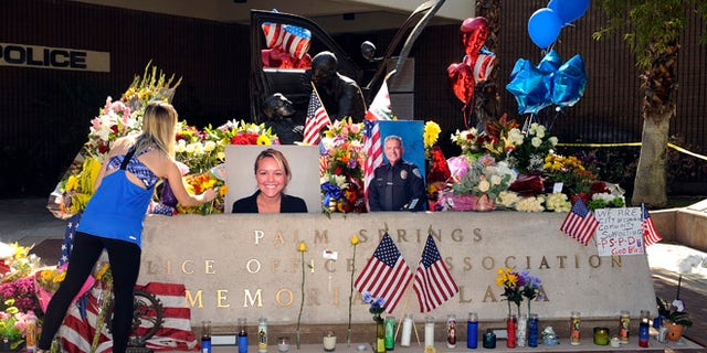 Kimberleigh Funkey, from Palm Springs, Calif., lays flowers by photos of slain Palm Springs police officers Lesley Zerebny and Jose "Gil" Gilbert Vega, in front of the police station in Palm Springs, Calif., Sunday, Oct. 9, 2016. (AP Photo/Rodrigo Peña)