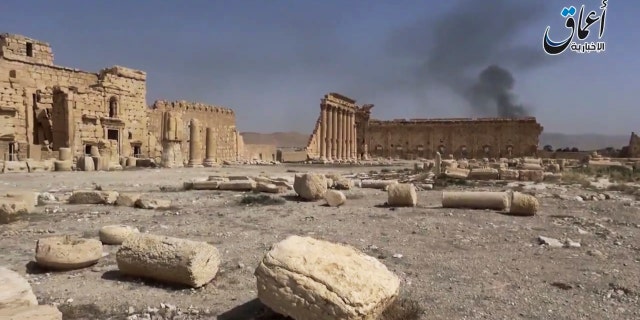 In this image made from a militant video posted on YouTube on May 26, 2015, which has been verified and is consistent with other AP reporting, smoke rises behind archaeological ruins in Palmyra, Syria. The video released by a media arm of the Islamic State group purportedly showed the archaeological ruins of Palmyra apparently undamaged.