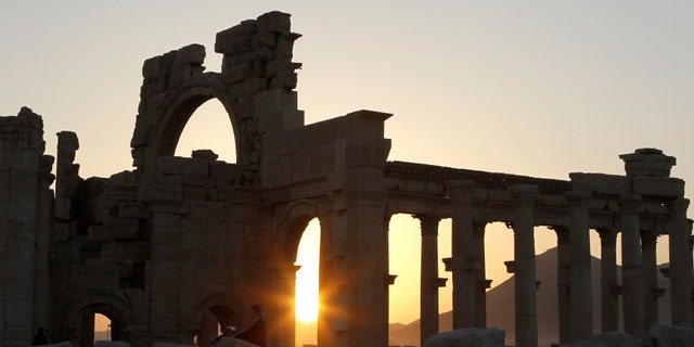 The sun sets behind ruined columns at the historical city of Palmyra, in the Syrian desert.