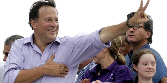 FILE- In this April 25, 2014 file photo, Juan Carlos Varela, presidential candidate for the Panamenista Party, waves to supporters during a campaign caravan through Arraijan on the outskirts of Panama City. Varela owes a debt of gratitude to a former adviser to John McCain’s ill-fated 2008 White House run for his come from behind victory in Panama’s presidential election. (AP Photo/Arnulfo Franco, File)