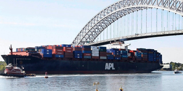 FILE - In this Tuesday, Sept. 21, 2010 file photo, the President Truman, a large cargo ship, passes under the Bayonne Bridge in Bayonne, N.J., as New Jersey Gov. Chris Christie, third left, front, and Lt. Gov. Kim Guadagno, fourth left, front, listen with others, as U.S. Rep. Albio Sires (D-NJ) talks about plans to raise the height of the bridge to accommodate the larger next generation of cargo ships. Residents in N.J. cities and towns are leery of the monster ships that will soon arrive because of a trade project thousands of miles away they believe will harm their air quality, roadways and waterways.  (AP Photo/Mel Evans,file)
