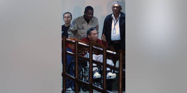 FILE - In this Dec. 11, 2011, file photo, Panama's ex-dictator Manuel Noriega gestures while being carried in a wheelchair by a police officer inside El Renacer prison in the outskirts of Panama City. Speaking to local television network the former Panamanian strongman broke his long silence in a interview from jail, aired on Wednesday, June 24, 2015, asking his compatriots to forgive actions by the military that culminated in the 1989 American invasion. (AP Photo/Esteban Felix, File)