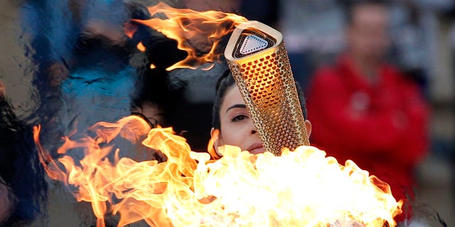 Actress Ino Menegaki, dressed as a high priestess, lights the torch at a ceremony in Panathinean stadium in Athens, Thursday, May 17, 2012. The torch begins its 70-day journey to arrive at the opening ceremony of the London 2012 Olympics, from the Greek capital, to cover about 8,000-mile (12,875-kilometer) on its progress over many parts of England to start the games. (AP Photo/Petros Giannakouris)