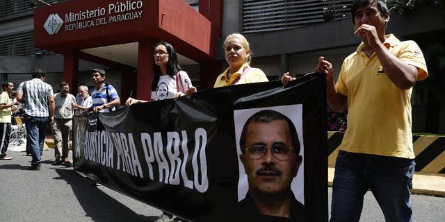 Journalists hold a banner that shows an image of slain reporter Pablo Medina, with a message that reads in Spanish; "Justice for Pablo" in a protest sparked by the death of radio journalist Gerardo Servian, outside the Attorney General's office in Asuncion, Paraguay, Friday, March 6, 2015. Medina, who focused on investigations exposing corruption and drug traffickers, was killed in October. Paraguayan officials say Servian was shot to death Thursday in a Brazilian city bordering a crime-ridden area that is a hotbed for drugs and arms smuggling. (AP Photo/Jorge Saenz)