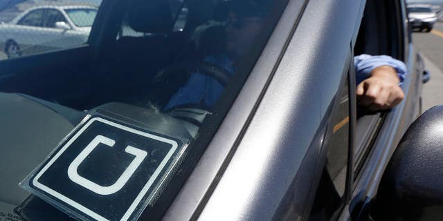 An Uber driver sits in his car parked near the San Francisco International Airport.