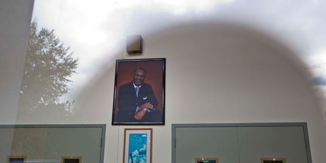 Oct. 14, 2014: The sun and clouds are reflected off a glass on the entrance of the Shiloh Missionary Baptist Church where a portrait of pastor Juan D. McFarland hangs on the wall in Montgomery, Ala. (AP/Brynn Anderson)