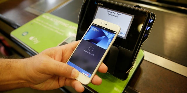 In this photo taken Friday, Oct. 17, 2014, Eddy Cue, Apple Senior Vice President of Internet Software and Services, demonstrates the new Apple Pay mobile payment system at a Whole Foods store in Cupertino, Calif. The new system launches on Monday. (AP Photo/Eric Risberg)
