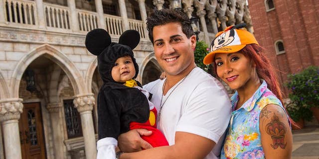 FILE - This image released by Disney shows TV personality Nicole "Snooki" Polizzi, right, from "Jersey Shore," with her fiance Jionni LaValle and their one-year-old son Lorenzo inside the Italy pavilion in the Epcot theme park, in this Sept. 27, 2013 file photo taken at Walt Disney World in Lake Buena Vista, Fla. The cast member of the reality series "Jersey Shore" and "Snooki and JWoww" spinoff intends to marry her fiance Jionni LaValle at the Venetian banquet hall in Garfield in the fall 2014. (AP Photo/Disney, Matt Stroshane, File)