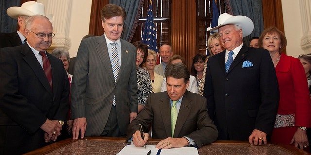 FILE - In this May 24, 2011 photo, Gov. Rick Perry, center, is flanked by state senators and representatives and anti-abortion supporters as he signs the sonogram bill at the state capitol in Austin, Texas.