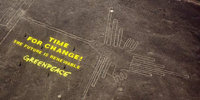 FILE - In this Dec. 8, 2014 file photo, Greenpeace activists stand next to large letters that spell out "Time for Change: The Future is Renewable" next to the hummingbird geoglyph in Nazca, Peru. A Peruvian prosecutor is investigating the suspected involvement of Greenpeace activist Mauro Fernandez in the publicity stunt that allegedly damaged the world-renowned Nazca lines that date to some 1,500 to 2,000 years ago. Authorities have said the fragile site was damaged by footprints. (AP Photo/Rodrigo Abd, File)