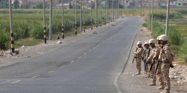 Soldiers stand guard on a highway that was the site of protests yesterday, near Cocachacra, Peru, Friday, May 15, 2015. Residents of this southern coastal valley are opposing the $1.4 billion Tia Maria project of Mexican-owned Southern Peru Copper because they fear the project would contaminate their crops. The protests that began in March have claimed the lives of two civilians and a police officer. (AP Photo/Martin Mejia)