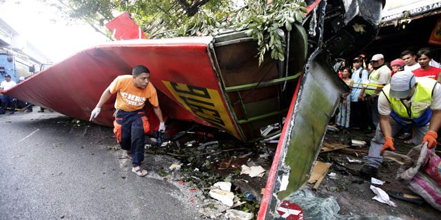 December 16, 2013: Investigators collect items from the wreckage of a passenger bus which plunged from an elevated highway known as the Skyway in suburban Paranaque southeast of Manila, Philippines.