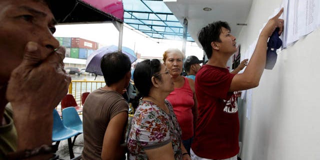 August 17, 2013: Relatives check the lists of survivors and the still-missing passengers and crew of the ill-fated passenger ferry MV Thomas Aquinas, outside the ticketing office of a shipping company. (AP Photo)