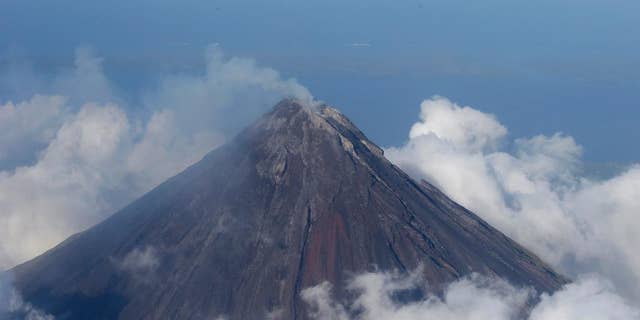 FILE - In this Feb. 26, 2014 file photo, smoke billows from the crater of Mayon volcano, one of the country's most active volcanoes, in Albay province about 550 kilometers southeast of Manila, Philippines. The Philippines' most active volcano has belched out lava fragments as big as a bus that rolled one kilometer (half a mile) down its slope, prompting authorities to start forcibly evacuating thousands of villagers, officials said Tuesday, Sept. 16, 2014. (AP Photo/Bullit Marquez, File)