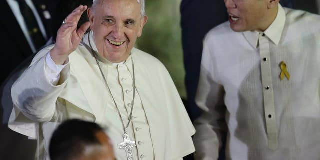 Pope Francis waves to well-wishers upon arrival from Sri Lanka Thursday, Jan. 15, 2015 at suburban Pasay city, south of Manila, Philippines. Pope Francis arrived for the first papal visit to the Philippines in 20 years. At right is Philippine President Benigno Aquino III who broke protocol to welcome the Pontiff. (AP Photo/Bullit Marquez)