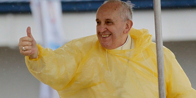 Wearing a yellow raincoat, Pope Francis gives a thumbs up to the faithful as he arrives in Tacloban, Philippines, Saturday, Jan. 17, 2015. A rain-drenched but lively crowd wearing yellow and white raincoats welcomed Pope Francis in the typhoon-ravage central Philippine city of Tacloban early Saturday, chanting "Papa Francesco, Viva il Papa!" (AP Photo/Wally Santana)