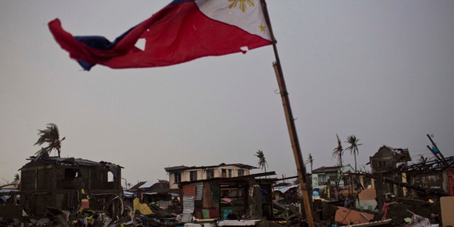 A flag of the Philippines flies over a destroyed neighborhood in Tacloban, Philippines on Friday Nov. 22, 2013. Hundreds of thousands of people were displaced by Typhoon Haiyan, which tore across several islands in the eastern Philippines on Nov. 8. (AP Photo/David Guttenfelder)