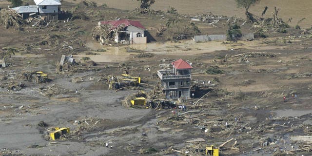 December 18, 2011: Remains of destroyed houses, toppled trucks and uprooted trees lie along a flood-hit area in Cagayan de Oro city, southern Philippines.