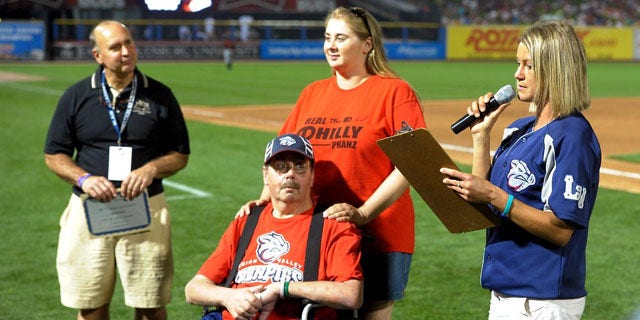 August 20, 2013: Kevin Reichel, left, of Reichel Funeral Home, watches along with Steve Paul, of Freemansburg Pa., and his daughter Robyn Paul as Lindsey Knupp, right, director of promotions and entertainment for the Lehigh Valley Iron Pigs minor league baseball team, reads the winning essay written by Steve Paul during the middile of the sixth inning at Coca-Cola Park, in Allentown, Pa. (AP Photo)