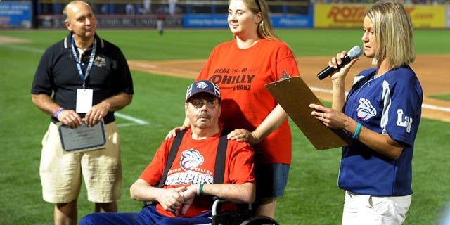 August 20, 2013: Kevin Reichel, left, of Reichel Funeral Home, watches along with Steve Paul, of Freemansburg Pa., and his daughter Robyn Paul as Lindsey Knupp, right, director of promotions and entertainment for the Lehigh Valley Iron Pigs minor league baseball team, reads the winning essay written by Steve Paul during the middile of the sixth inning at Coca-Cola Park, in Allentown, Pa. (AP Photo)