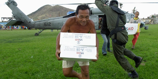 Nov. 20: U.S. Navy Aviation ASW Operator Third Class Caleb Rausch, of Durham, North Carolina, dodges typhoon victims carrying aid from a U.S. Navy Seahawk helicopter in Palo, Philippines.