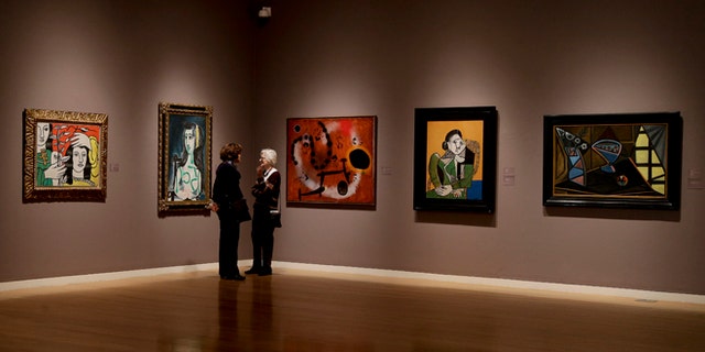 Prospective buyers talk amongst paintings by Pablo Picasso, Joan Miro and Fernand Leger during a preview exhibition for Sotheby's Spring Evening Sale of impressionistic and modern art, Friday, May 2, 2014, in New York. The sale will begin on May 7. (AP Photo/Julie Jacobson)