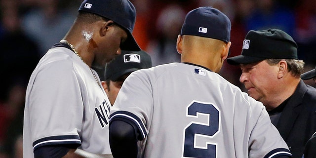Home plate umpire Gerry Davis, right, confers on the mound with New York Yankees starting pitcher Michael Pineda, left; shortstop Derek Jeter (2); and others in the second inning of a baseball game against the Boston Red Sox at Fenway Park in Boston, Wednesday, April 23, 2014. Pineda was ejected after umpires found with a foreign substance on his neck.(AP Photo/Elise Amendola)