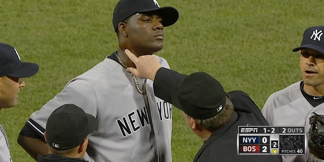 In this April 23, 2014 photo taken from video and provided by ESPN, home plate umpire Gerry Davis touches the neck of New York Yankees starting pitcher Michael Pineda in the second inning of the Yankees' baseball game against the Boston Red Sox at Fenway Park in Boston. Pineda was ejected after umpires found a foreign substance on his neck. (AP Photo/ESPN)