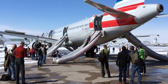 In this photo provided by Andy Long passengers slide down emergency chutes after an American Airlines flight from Charlotte, N.C., soon after landing in Denver, Wednesday, March 4, 2015. The plane, operated by U.S. Airways, was taxiing to the gate at Denver International Airport when smoke was reported in the aircraft just before noon, airport spokeswoman Mindy Crane said. The captain ordered that the chutes be activated, and the passengers and crew members slid down to safety from Flight 445 before being taken by bus to the concourse, said Crane and American Airlines spokeswoman Andrea Huguely. (AP Photo/Andy Long)
