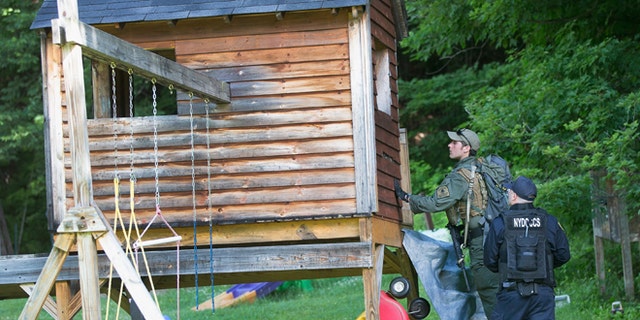 Law enforcement personnel search a child's playhouse as the manhunt for convicted murderers, Richard Matt and David Sweat, on June 26, 2015 in Chasm Falls, New York. (Photo by Scott Olson/Getty Images)