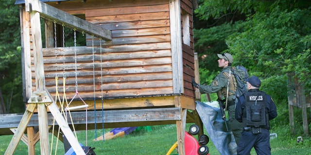 Law enforcement personnel search a child's playhouse as the manhunt for convicted murderers, Richard Matt and David Sweat, on June 26, 2015 in Chasm Falls, New York. (Photo by Scott Olson/Getty Images)