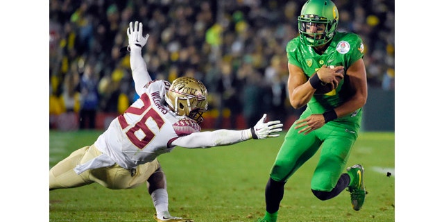 Jan. 1, 2015: Oregon quarterback Marcus Mariota, right, scores past Florida State defensive back P.J. Williams during the second half of the Rose Bowl NCAA college football playoff semifinal in Pasadena, Calif. (AP Photo/Mark J. Terrill)