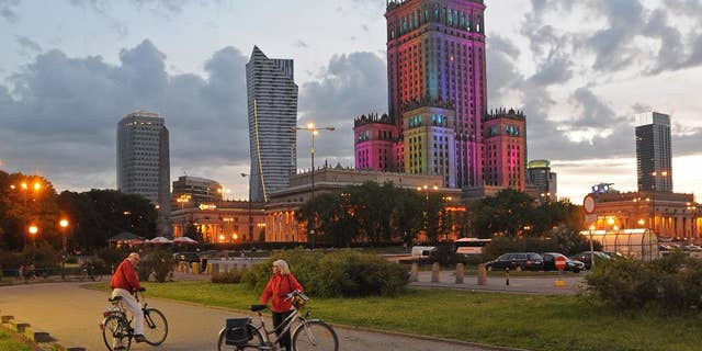 The communist era Palace of Culture, colorfully illuminated, is surrounded by modern skyscrapers, in Warsaw, Poland, Saturday, May 31, 2014. (AP Photo/Alik Keplicz)