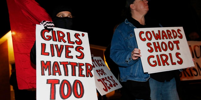 Nazzi McDonnell, left, of Colorado Springs, Colo., joins other participants in waving placards during a vigil near the scene of the early morning fatal shooting of a young woman who hit and injured a Denver Police Department officer while driving a stolen vehicle Monday, Jan. 26, 2015, in northeast Denver. (AP Photo/David Zalubowski)