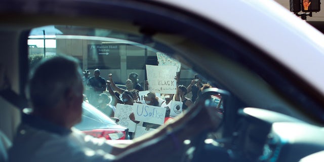 A driver passes demonstrators as they block an entrance to Lenox Square Mall during a Black Lives Matter protest in Atlanta, Saturday, Sept. 24, 2016, in response to the police shooting deaths of Terence Crutcher in Tulsa, Okla. and Keith Lamont Scott in Charlotte, N.C. The Black Lives Matter chapter of Atlanta is boycotting major retailers following the recent police shooting deaths involving black men. (AP Photo/Branden Camp)