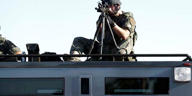 Aug. 13, 2014: A member of the St. Louis County Police Department trains his weapon on a relatively small group of protesters in Ferguson, Mo.