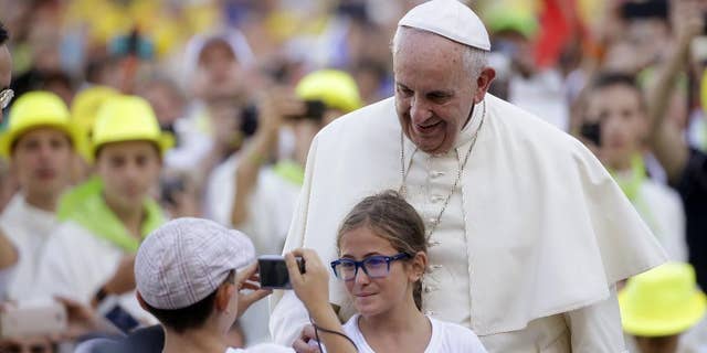 FILE - In this Tuesday, Aug. 4, 2015, file photo, Pope Francis poses for a photo as he arrives in St. Peter's Square at the Vatican for an audience with with Altar boys and girls. Francis thrills Democrats with his teachings on climate change, social justice and immigration. At the same time, his message on life and the Catholic Church's traditional opposition to abortion comfort Republicans. Both Democrats and Republicans are looking forward to Francis' remarks to Congress next month. (AP Photo/Gregorio Borgia, File)