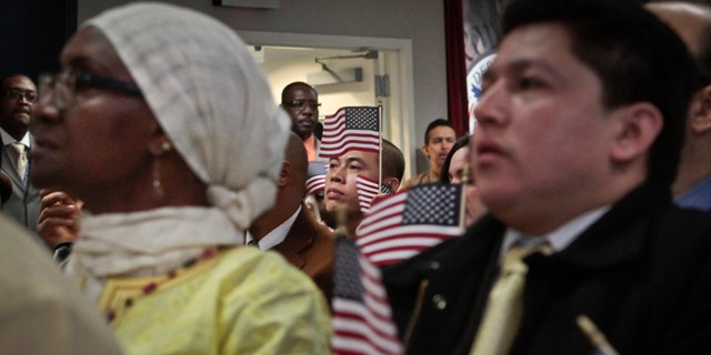 Immigrants hold miniature U.S. flags as they listen to a video broadcast from President Barack Obama during a naturalization ceremony attended by Mayor Michael Bloomberg on Wednesday, Dec. 18, 2013 in New York. A new study finds that Hispanics and Asian-Americans say getting relief from deportations is more important for many of the 11 million immigrants here illegally than creating a pathway to U.S. citizenship. (AP Photo/Bebeto Matthews)