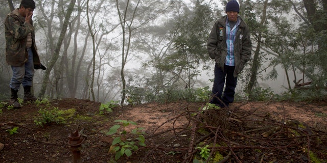 In this June 25, 2015 photo, Guarani environmental health specialist Albino Flores, right, and farmer David Benitez stand at the site of an unsealed oil well, left behind by the state-owned YPFB oil company inside Aguarague National Park in southeastern Bolivia. Benitez, who lives in the park and grazes his cattle among the wells, said the odor is much stronger in the summer, when theres no water to wash the oil downstream. (AP Photo/Juan Karita)