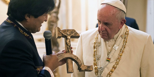 Bolivian President Evo Morales presents Pope Francis with a crucifix carved into a wooden hammer and sickle, in La Paz, Bolivia, Wednesday, July 8, 2015. The crucifix is a replica, originally designed by Jesuit activist Luís Espinal, who was assassinated in 1980 by suspected paramilitaries during the months that preceded a military coup. Even though the Vatican was not expecting the unusual gift, it is seeking to explain the "Communist crucifix" given to Francis, saying it's a symbol of dialogue and not an offensive melding of faith and ideology. (L'Osservatore Romano/Pool Photo via AP)