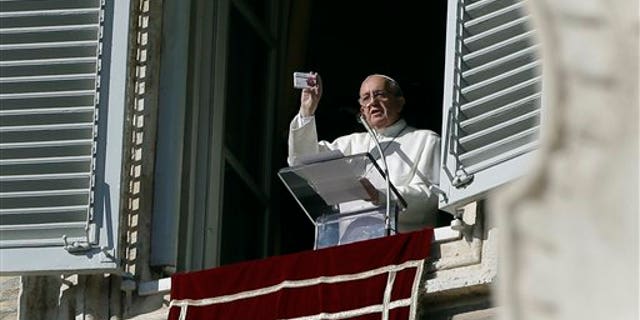 Pope Francis shows a rosary in a box designed to resemble a packets of pills, during his traditional Sunday's appearance from his studio overlooking St. Peter's Square at the Vatican, Sunday, Nov. 17, 2013. Joking that he's like a pharmacist, Pope Francis is promoting prayer as medicine for the heart. (AP Photo/Gregorio Borgia)