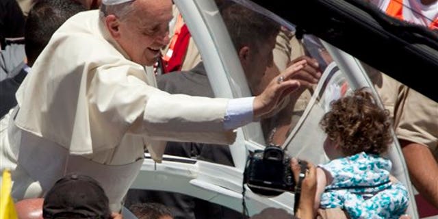 May 25, 2014: Pope Francis reaches to a girl after a mass in Bethlehem, West Bank. (AP)