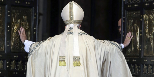 Pope Francis pushes open the Holy Door of St. Peter's Basilica, formally launching the Holy Year of Mercy, at the Vatican, Tuesday, Dec. 8, 2015. The 12-month jubilee emphasizes what has become the leitmotif of his papacy: to show the merciful and welcoming side of a Catholic Church more often known for its moralizing and judgment. (AP Photo/Gregorio Borgia)