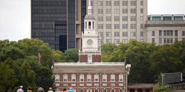 FILE – Tourists walk in view of Independence Hall Thursday, mes de julio 30, 2015, en Filadelfia.