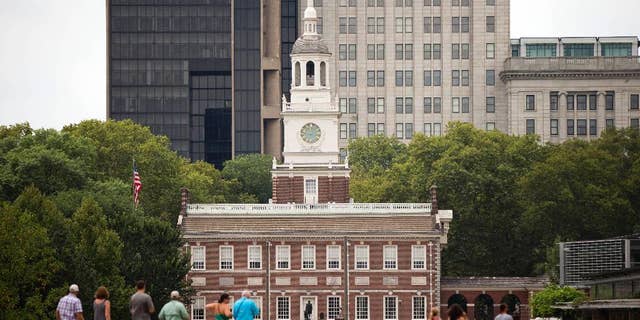 FILE – Tourists walk in view of Independence Hall Thursday, July 30, 2015, in Philadelphia.