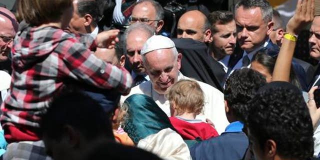 FILE - In this April 16, 2016 file photo, Pope Francis meets migrants at the Moria refugee camp on the Greek island of Lesbos. The pope, in his annual message for the World Day of Migrants and Refugees on Thursday, Oct. 13, 2016, denounced the forced repatriation of unaccompanied children migrants who flee wars and poverty, saying countries should try to meet their needs rather than return them to uncertain futures back home. (AP Photo/Petros Giannakouris, File)
