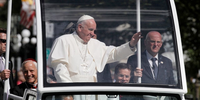 Pope Francis waves to the crowd from the popemobile during a parade in Washington, Wednesday, Sept. 23, 2015.