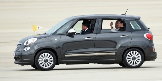 FILE - In this Sept. 22, 2015, file photo, Pope Francis waves from inside a Fiat 500 as he departs Andrews Air Force Base in Md. One of the two Fiats used by Pope Francis during this visit to Philadelphia last year is going up for auction. The car will be up for bid as part of the Philadelphia Auto Show black tie gala on Jan. 29. Bids will be accepted in person and online. (AP Photo/Susan Walsh, File)