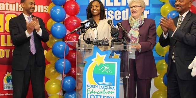 In this undated photo provided by the North Carolina Education Lottery, shows Powerball jackpot winner Marie Holmes, second from left, after she received a check from North Carolina Education Lottery executive director Alice Garland, second from right, in Raleigh, N.C. To the left is financial adviser Dexter Perry and attorney Charles Francis, right. (AP Photo/North Carolina Education Lottery)