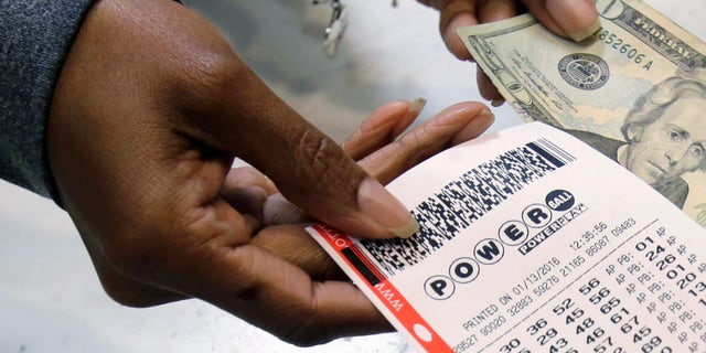 FILE - In this Jan. 13, 2016 file photo, a clerk hands over a Powerball ticket for cash at Tower City Lottery Stop in Cleveland. Powerball estimates that its jackpot for the May 4, 2016, drawing is $348 million. (AP Photo/Tony Dejak, File)